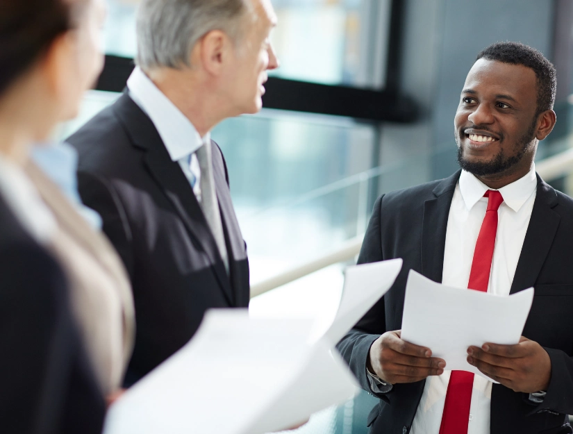 Two business professionals in suits engage in discussion while reviewing documents in a modern office setting
