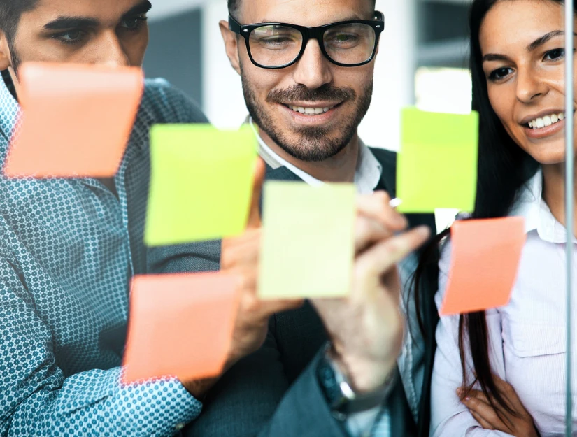 A group of people discussing ideas, holding colorful sticky notes
